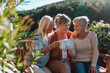 © Halfpoint - Senior female friends enjoying coffee together on cabin terrace getaway.