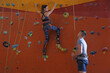 © New Africa - Instructor helping woman on climbing wall in gym