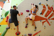 © New Africa - Athletic man and woman climbing wall in gym, back view
