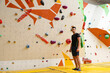 © New Africa - Athletic young man near climbing wall in gym. Space for text