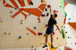 © New Africa - Athletic young man climbing wall in gym. Space for text
