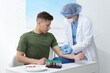 © New Africa - Nurse drawing blood sample of patient's vein with syringe at white table in clinic