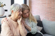 © luciano - Granddaughter Comforting Grandmother At Home Showing Family Support, Love And Elder Care On Couch