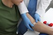 © New Africa - Nurse putting adhesive bandage on patient's arm after drawing blood sample at table in clinic, closeup