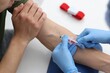 © New Africa - Nurse drawing blood sample of patient's vein with syringe at white table in clinic, closeup