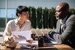 © Davor - Two business professionals discussing reports outside an office