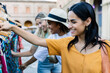 © Xavier Lorenzo - Multiracial young female friend smiling while shopping outdoors. Confident woman enjoying travel and leisure time in city market. Lifestyle and tourism concept.