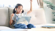 © Smile Studio AP - Cute Asian girl using a digital tablet on sofa at home, online learning, homeschooling, technology lifestyle and modern childhood education concept.