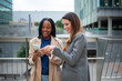 © Miquel - Two diverse businesswomen collaborating using smartphone technology