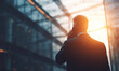 © Hasyim - Businessman in suit talking on phone against modern building at sunset
