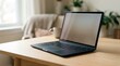 © ilham - Modern laptop computer on a wooden desk in a bright, cozy home office setting with a coffee mug and blurred background plants