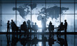 © Supardi - Silhouetted group meeting in modern office with world map backdrop