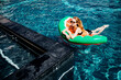 © Vlad - Young hot woman resting at swimpool. Side view of sexy gorgeous girl on swim ring posing on camera. Swimming alone in water at resort spa place. Summertime sunshine.
