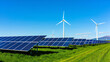 © PG Studio - Large solar power plant and wind turbines on a green grass field with mountain view, turbines