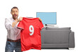 © Ljupco Smokovski - Man holding up a red football jersey with the number nine