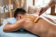 © Meow Creations - Male client lies on his stomach while receiving a professional back waxing treatment in a salon