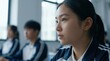 © tonstock - A focused young Asian female student listening to a lecture in a classroom with classmates.