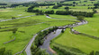 © Travel 'n' Lifestyle - View of the winding River Ure and a stone bridge crossing a road amidst the lush green pastures and stone walls of the Yorkshire Dales in Hawes, England, United Kingdom.