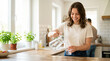 © Xenia - Smiling young woman pouring fresh water from a pitcher into a glass. Female hydrating in a bright modern kitchen. Healthy lifestyle and wellness concept