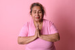 © Luis Fernando Dávila - Peaceful Senior Latina Woman Praying on Pink Background