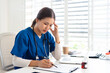 © Fahng - Stressed Female doctor nurse sit by laptop computer while reviewing patient medical charts at the clinic office.