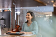 © fizkes - Smiling female receptionist working on computer at reception desk, verifying reservation details and guest records, preparing report, organizing hotel daily administrative workflow tasks at front desk