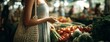 © Snowstudio - Young woman choosing fresh vegetables at market with casual attire