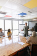 © fizkes - Adult businessman giving presentation to multiethnic team, explaining strategy and ideas during group meeting in office conference room. Business training, executive coaching, corporate negotiations