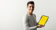 © XM7MDX - A smiling young man holding a tablet with a bright yellow screen in a plain white background