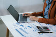 © Kieng - Business analyst working on laptop while reviewing financial reports and business data in modern office workspace.