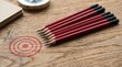 © Nusrat - Set of sharpened red pencils aligned perfectly pointing towards red concentric circular target on textured wooden table background depicting strategic planning success and goal attainment.