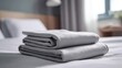 © SiyamBin - Neat stack of folded grey cotton sheets on a bed in a minimalist bedroom interior