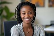 © SEcho - Beautiful young black woman with dreadlocks and wearing glasses smiles confidently while looking directly at the camera in an office setting.