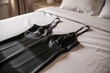 © starush - Black satin slip dress laid on white bed with soft natural bedroom light