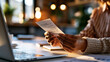 © Kateryna - A pair of European hands holds a soft glowing donation receipt on a bright modern desk near a calm laptop in soft daylight donation receipt faceless detail softly