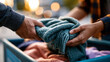 © Kateryna - A pair of European hands offers soft blankets to a bright donation box in a calm community aid moment in soft daylight clothes giving faceless detail softly defocused backdrop