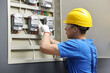 © New Africa - Electrician checking fuse box with electrical meters indoors