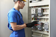 © New Africa - Electrician with screwdriver checking electrical meter indoors