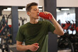 © New Africa - Man with sweat on his body drinking water in gym
