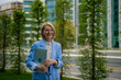 © Jelena - Mature businesswoman holding laptop walking in city park