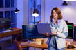 © Pixel-Shot - Happy female programmer with headphones and laptop working in office at night