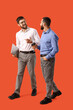 © Pixel-Shot - Happy businessmen with laptop and cup of coffee negotiating on orange background