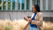 © Miquel - Young black businesswoman smiling holding digital tablet outdoors