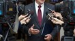 © alvi - Businessman in suit and tie speaking to multiple microphones from various news reporters and cameras