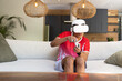 © wavebreak3 - Man wearing red sports shirt and VR headset, holding white controller on light sofa in kitchen