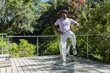 © wavebreak3 - African American man balancing on exercise mat on wooden deck near metal railing wearing sportswear