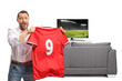 © Ljupco Smokovski - Sports fan cheering with a football jersey in front of tv