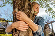 © Westend61 - Woman in garden hugging a tree