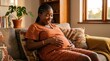 © Fiverr/fazilazia703 - Happy pregnant Black woman sitting on a cozy sofa at home, gently cradling her baby bump in warm afternoon light, displaying maternal love, comfort, and peaceful pregnancy journey.