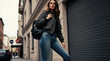 © Pete - Woman in bomber jacket, jeans and sneakers walks in city street. She wears backpack and looks confidently. Urban lifestyle and modern fashion.